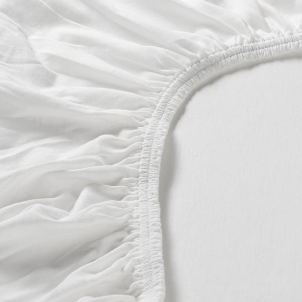 Primo piano di un fresco lenzuolo bianco con angoli che mostra bordi elastici di qualità per una vestibilità sicura e liscia.