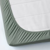 Un lenzuolo con angoli in jersey di cotone verde, che si allunga per adattarsi saldamente agli angoli del materasso.