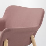 Primo piano di una sedia imbottita rosa con gambe in legno, che mostra il suo design elegante e il tessuto di alta qualità.