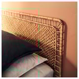 Letto VEVELSTAD con testiera in rattan, trama incrociata, contro parete arancione.