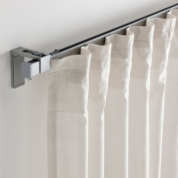 Le tende beige sono appese a un binario VIDGA utilizzando accessori a parete per bloccare la luce.