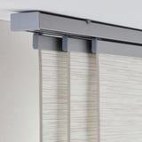 Sistema di binari per tende grigie montato a parete con tende verticali bianche.