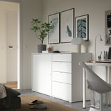 Ufficio domestico moderno e minimalista. Mobile contenitore bianco, sedia grigia, stampe d'arte, pianta, lampada.