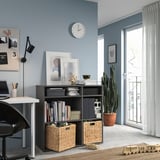 Moderno home office blu con mobile contenitore VIHALS grigio scuro, scrivania bianca, sedia nera, orologio da parete e grande finestra con tende bianche.