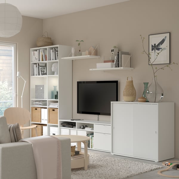 Soggiorno moderno con mobili contenitori VIHALS bianchi, tv, divano beige e oggetti decorativi.