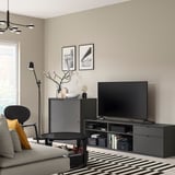 Soggiorno moderno con panca TV VIHALS, tv a schermo piatto, divano grigio, sedia nera, tavolino, arredamento e lampadario.