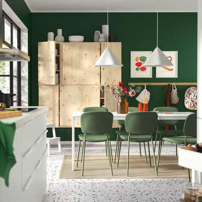 Set da pranzo moderno in verde: tavolo allungabile in pino, sedie in tessuto verde, pavimento in terrazzo, lampade a sospensione bianche, pareti verdi, arredamento minimalista.