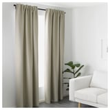 Tende oscuranti della stanza, atmosfera accogliente. Il tessuto beige offre privacy, riduzione della luce. Poltrona bianca, pianta, arredamento minimalista.