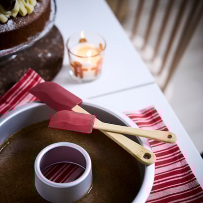 Un set di spatole da cucina rosse con manici in bambù, una più grande e una più piccola, progettate per l'uso da parte di adulti e bambini.