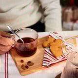 A mano mescola la bevanda speziata, bicchiere su tavola di legno con biscotti.