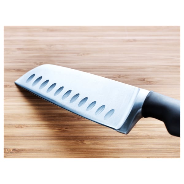 Un coltello di alta qualità con bordi seghettati giace su una tavola di legno. La lama affilata e l'impugnatura ergonomica garantiscono un taglio preciso.