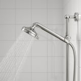 Un soffione cromato con molteplici opzioni di getto: nebulizzazione delicata, getto completo e getto massaggiante, fissato a un braccio flessibile, in un ambiente bagno.