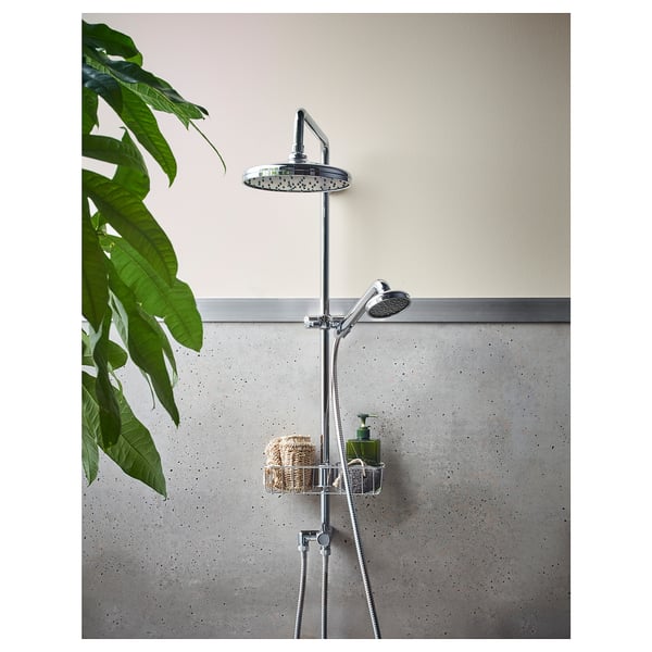 Bagno moderno con soffione cromato VOXNAN e unità portatile su binario, con parete maculata grigia e grande pianta verde.