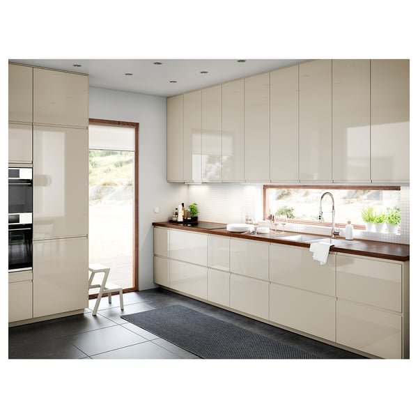 Cucina moderna con armadi bianchi lucidi, piano di lavoro in legno ed elettrodomestici da incasso. Ampia finestra sopra il lavandino.