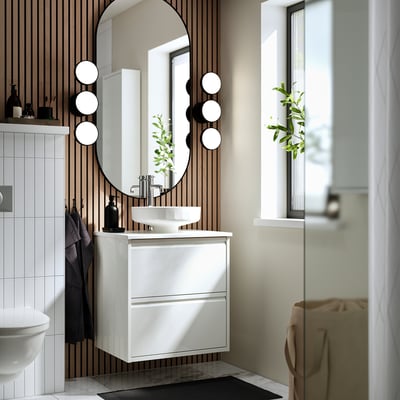 Modern white bathroom: round mirror, sleek cabinet, bowl sink, circular lights.