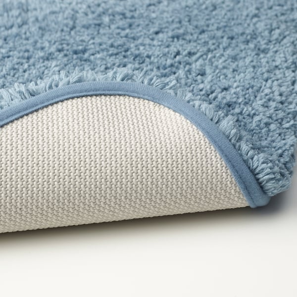 Close-up of plush, light blue bath mat, showcasing soft texture and sturdy white back.