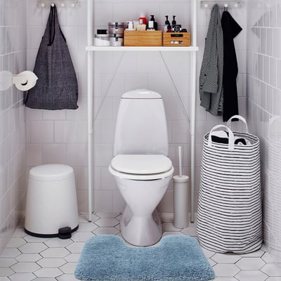 Small blue ALMTJÄRN mat, soft & absorbent, fits perfectly near toilet in clean, minimalist bathroom.