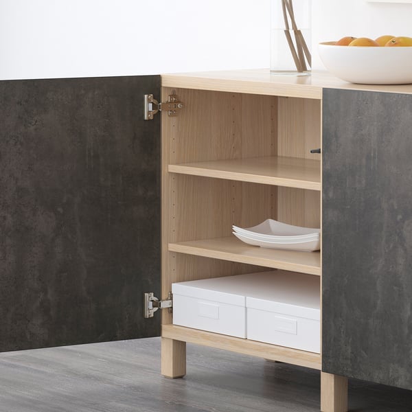 Open wooden cabinet with shelves holding a white bowl and boxes, part of IKEAs BESTÅ storage series.