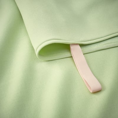 Folded light green blanket with soft pink loop, showcasing quality fabric and craftsmanship.