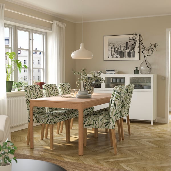 Dining area with EKEDALEN extendable table, green chairs, pendant lamp, vase, cabinet, window, radiator.