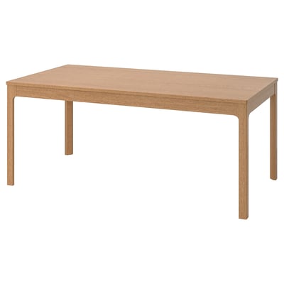 A light brown ikea EKEDALEN wooden dining table with a rectangular top and four corner legs.