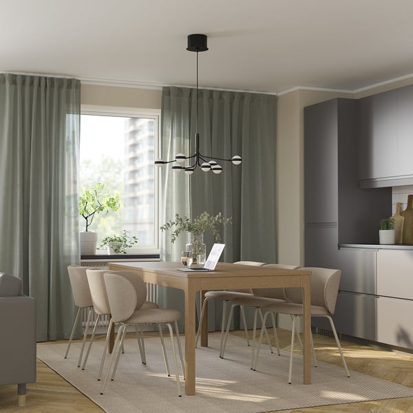 Modern wooden dining set with pendant light, curtains, and green view.