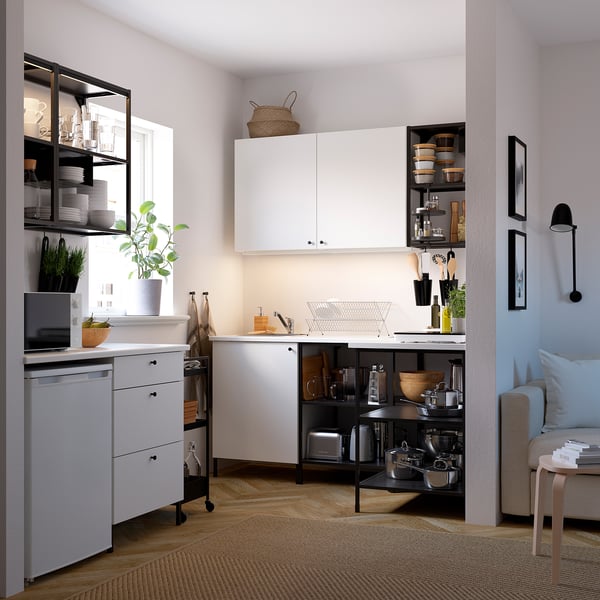 Small white kitchen with hanging shelves, green plant, and open storage, modern design.