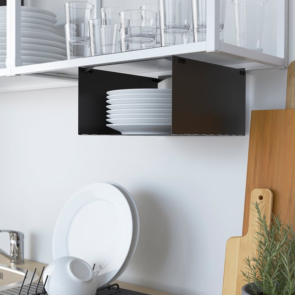 Kitchen shelf with glassware and black drawer, white plates stacked inside.