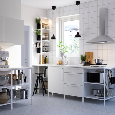 Modern white kitchen with stainless steel appliances, hanging lighting, and open shelving.