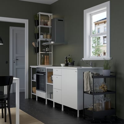 Modern compact kitchenette: white cabinets, dark floor, stainless sink & various jars & pots; open shelves and counter space for daily use.