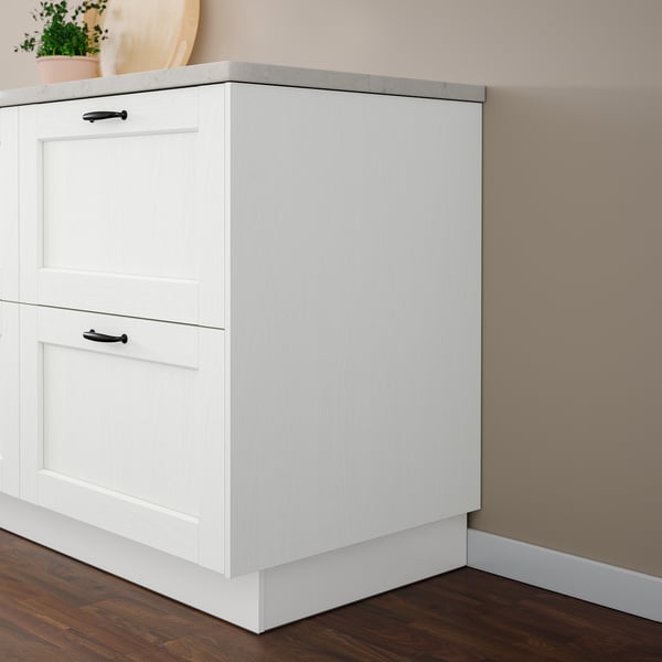 White ENKÖPING cabinet, sleek & modern, fits neatly in corner. Smooth surface, durable foil, classic design. Small plant on top.