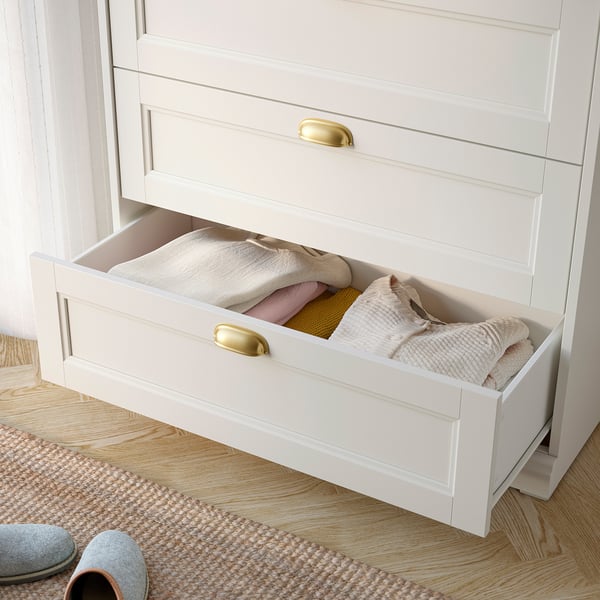 White drawer open, showing folded clothes inside. Brass handle visible. Part of FÅGELFJÄLLET bedroom series.