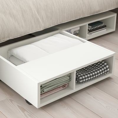 Under-bed storage unit with castors, holding folded blankets and linens, rolled out for easy access.