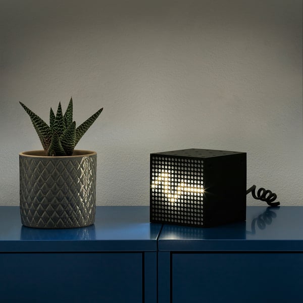 Cube lamp on blue shelf, sound-reactive. Beside, black planter with succulent.