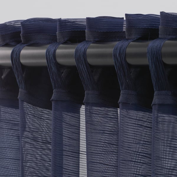 Sheer curtains hang neatly, allowing daylight while ensuring privacy. Metal rod and tabs visible.