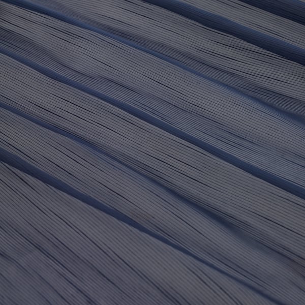 Sheer, textured curtains, crafted from recycled pet bottles, exhibit elegant diagonal stripes and a refined pleated appearance.