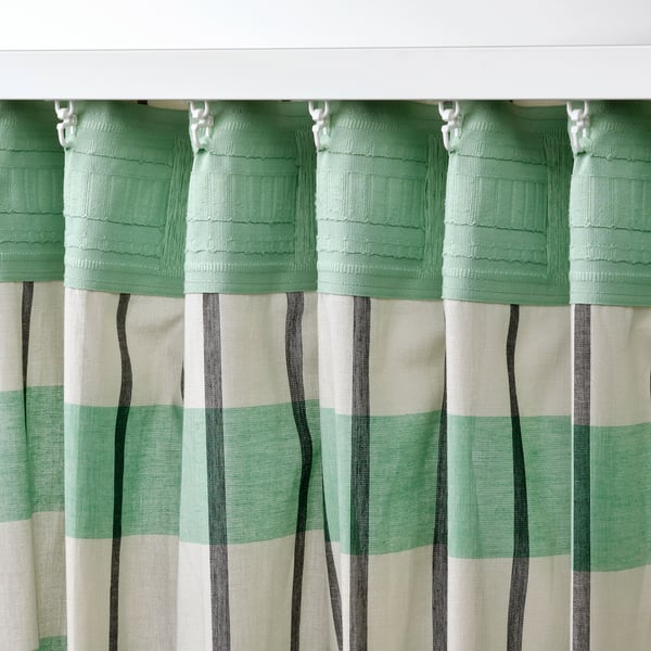 Green and white striped curtains with black lines hang from hooks. They let light through while maintaining privacy, ideal for wide windows.