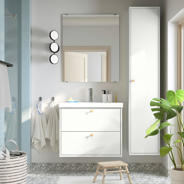 Modern white bathroom with HAVBÄCK cabinet, mirror, lights, plant, and stool. Towels near shower.