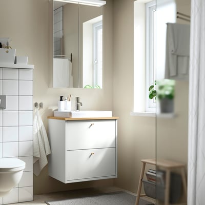 A modern white bathroom with HAVBÄCK vanity, bamboo counter, mirror, and towel.