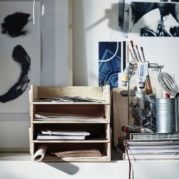 Wooden letter tray, KLÄMMEMACKA, natural, with multiple compartments, holding papers on a desk with art supplies nearby.