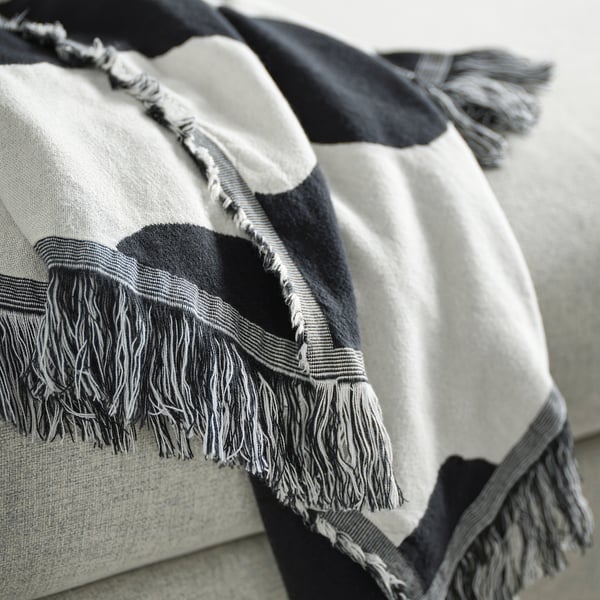 Folded throw blanket with large dots and fringe edges shown in close-up.