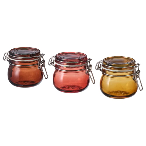 Three KRÖSAMOS jars in brown, red, and yellow with metal lids.