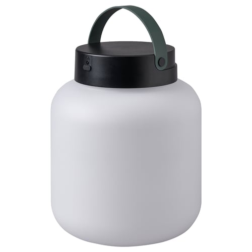 Depicts a LÄNSPORT portable lamp in white. It a sleek, round shape with a black lid and green handle, designed for both indoor and outdoor use.