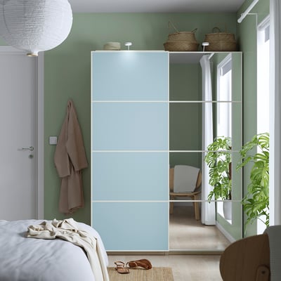 Light blue mirrored closet doors, modern, sliding, fit pax, with green walls, white bed, storage, plant, sandals.