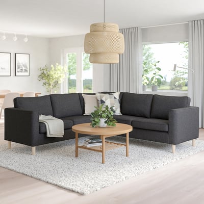 Modern living space with dark grey PÄRUP sectional sofa, light wood coffee table, round rug, large window, and hanging light.