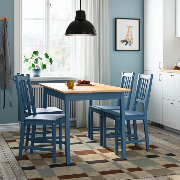 Modern kitchen with PINNTORP blue dining set. Pine wood, by the window, with mugs and apples. White curtains, giraffe art, cosy decor.