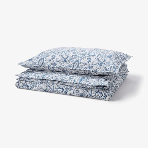 A stack of blue and white paisley printed RODGERSIA pillows. The soft cotton-blend pillows feature intricate designs.