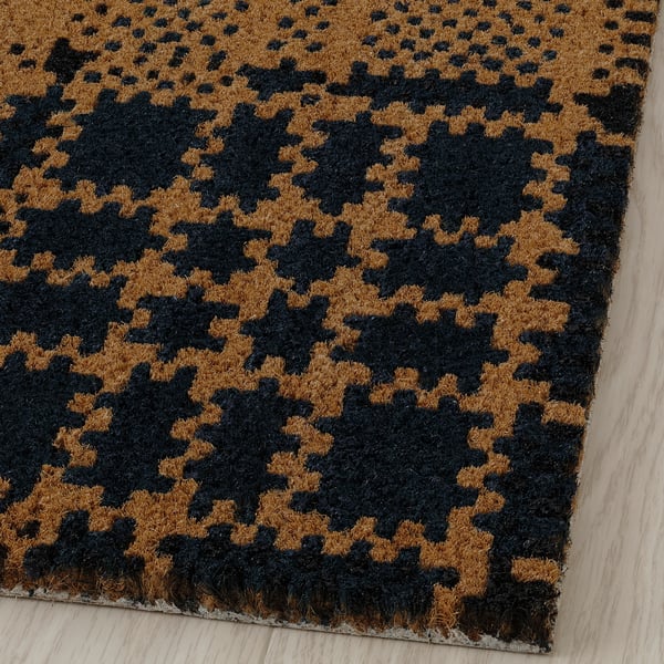 Black and tan chequered doormat, made of coir, placed at entrance.