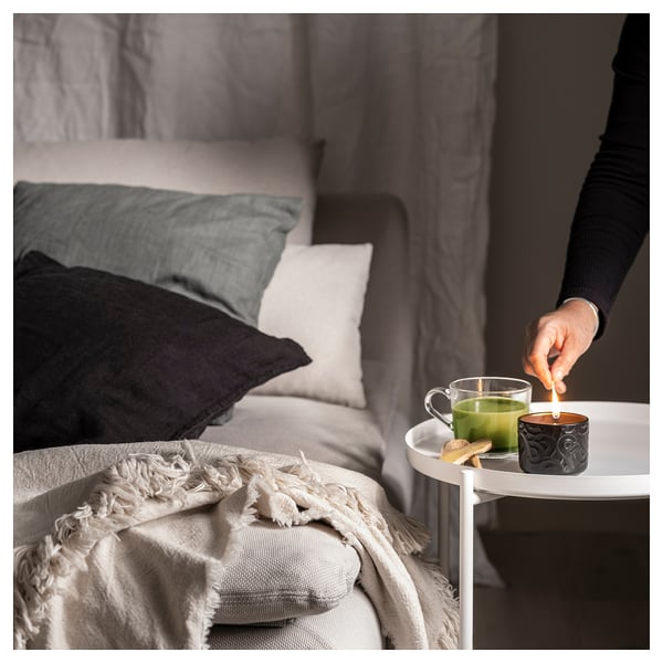Lighting SÖTRÖNN candle beside bed, fresh green tea & ginger scent.