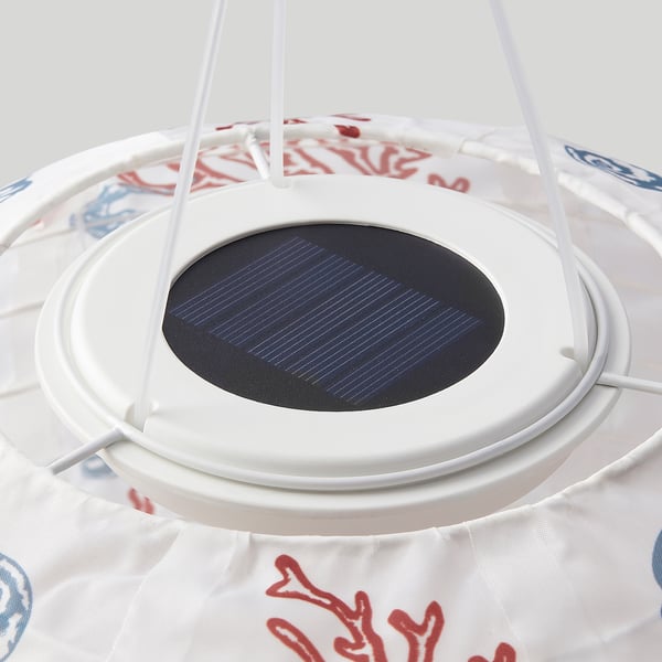 Solar-powered lantern with white patterned shade. Circular solar panel on top, suspends by white strings.